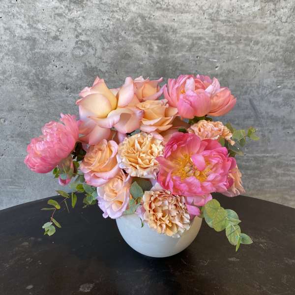 Pink and peach floral arrangement in a white vase