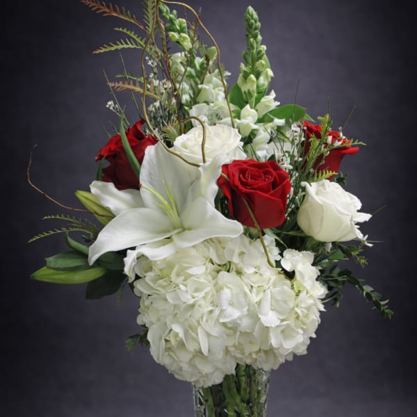 Red and white roses with lilies and hydrangeas in a glass vase
