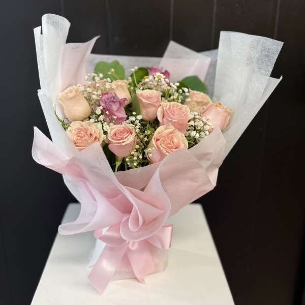 Bouquet of pale pink roses wrapped in pink and white paper