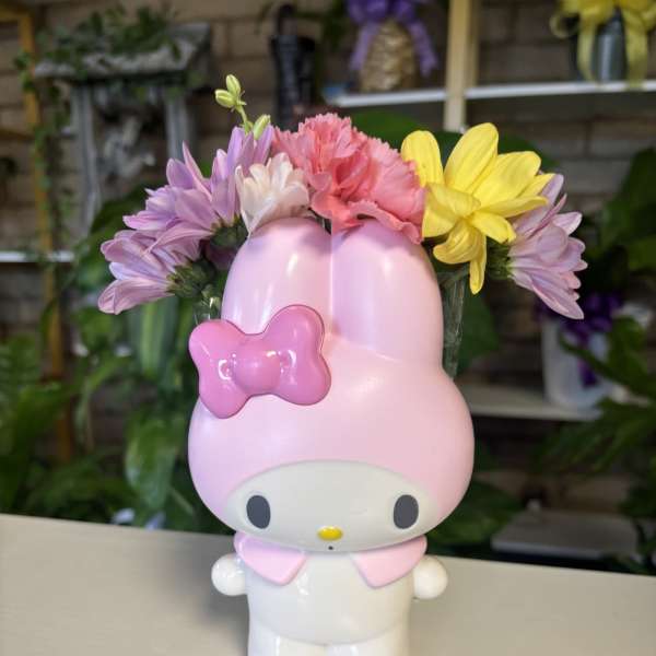 Pink Hello Kitty figurine holding a small bouquet of daisies