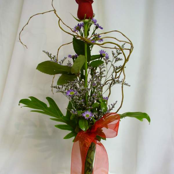 Tall red rose arrangement with purple filler flowers in a clear vase