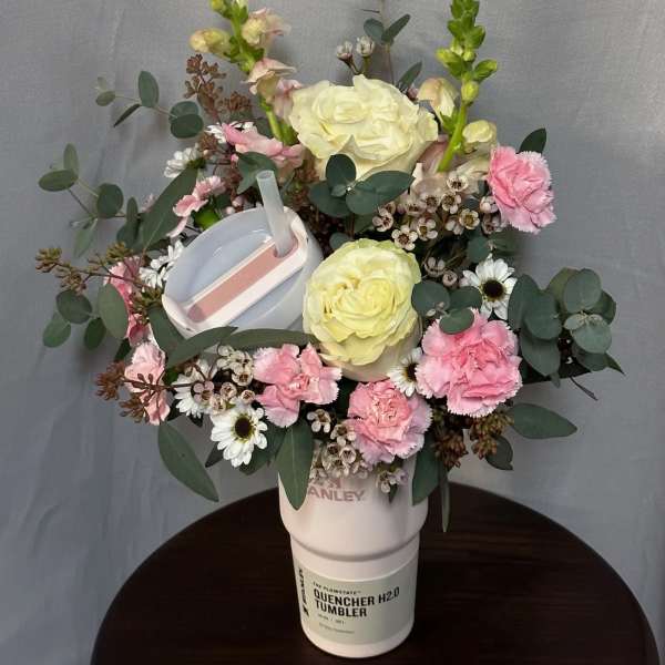 Floral arrangement in a white tumbler with pink and cream blooms