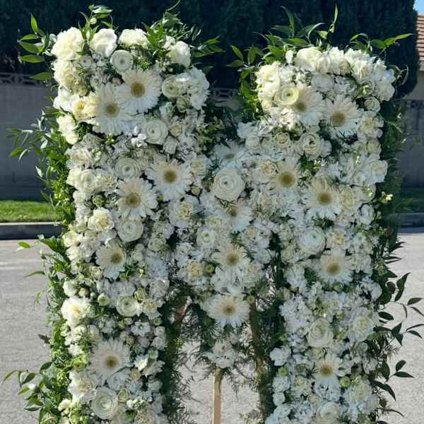 Large white floral standing spray shaped like a letter M on an easel