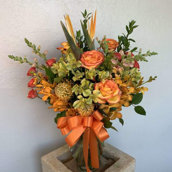 Orange and yellow mixed bouquet in a glass vase with a ribbon