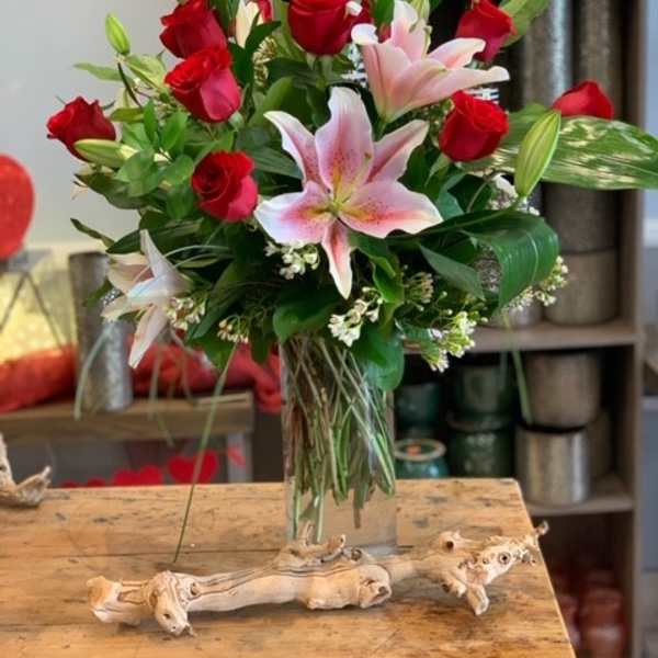 Bouquet of red roses and pink lilies in a clear glass vase