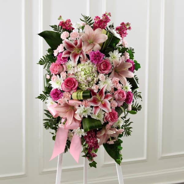 Pink and white floral standing spray on an easel with a ribbon