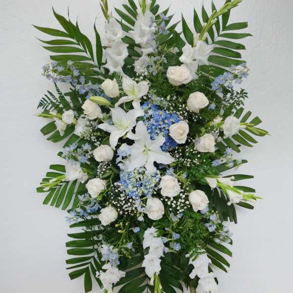 Standing floral spray with white lilies, roses, and blue accents