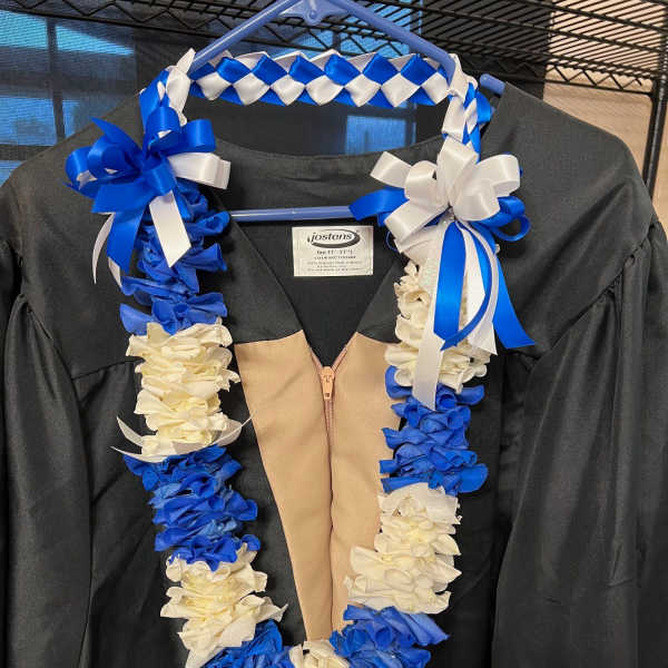 Blue and white lei draped over a black graduation gown