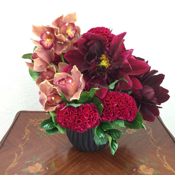 Deep red and peach floral arrangement in a black vase