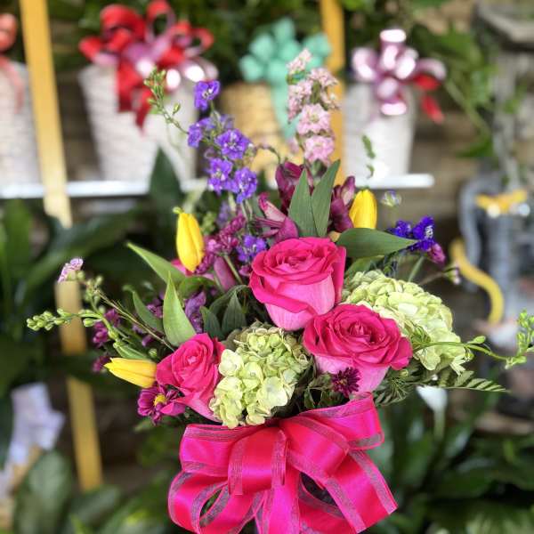 Pink roses and mixed flowers in a vase with a bright ribbon bow