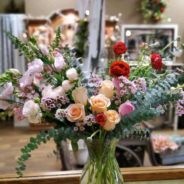 Mixed bouquet of roses and pink blooms in a clear glass vase