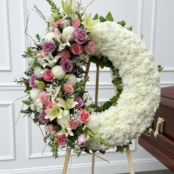 Large floral funeral wreath with white and pink flowers on an easel