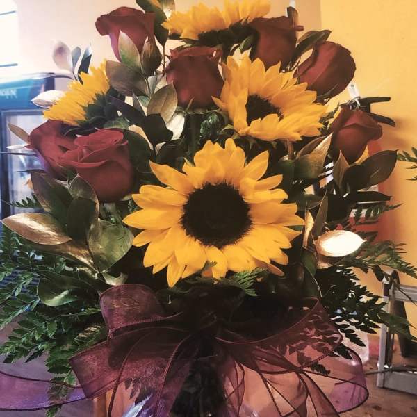 Bouquet of yellow sunflowers and burgundy roses in a glass vase