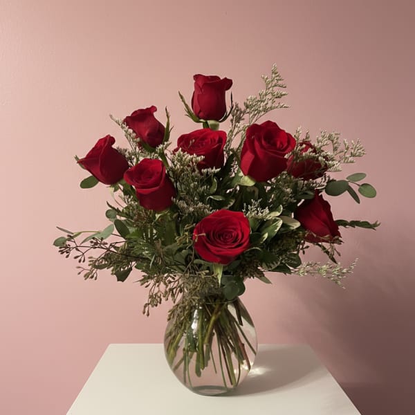Arrangement of red roses with white filler flowers in a round clear glass vase