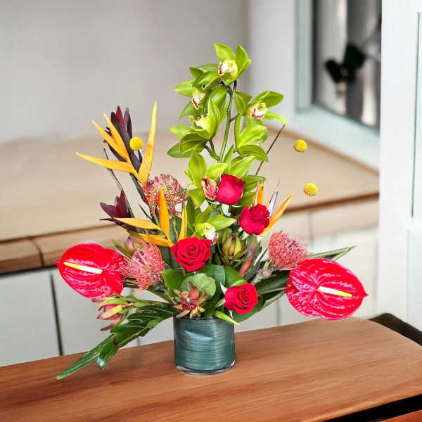 Tropical bouquet with red roses and pink anthuriums in a glass vase