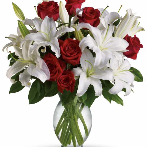 Red roses and white lilies arranged in a clear glass vase