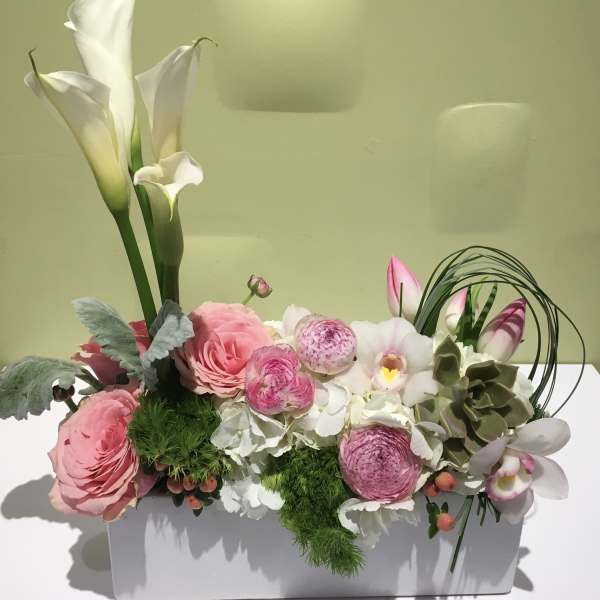Pink and white floral arrangement in a white rectangular container