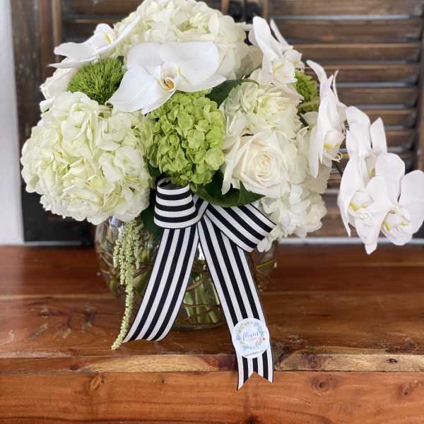 White floral arrangement with orchids and hydrangeas in a glass vase