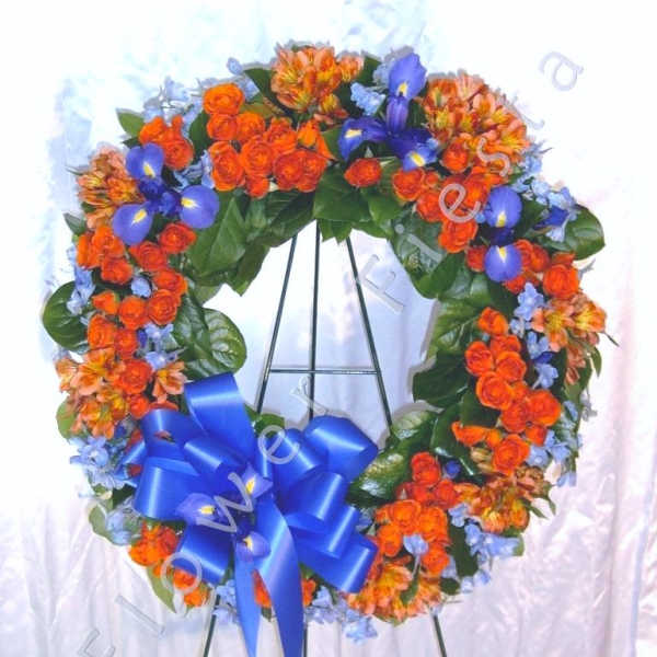 Heart-shaped floral wreath with orange and blue flowers on an easel