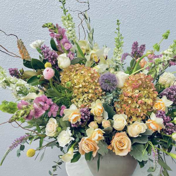Large mixed floral arrangement in a round vase with pink, white, and peach blooms