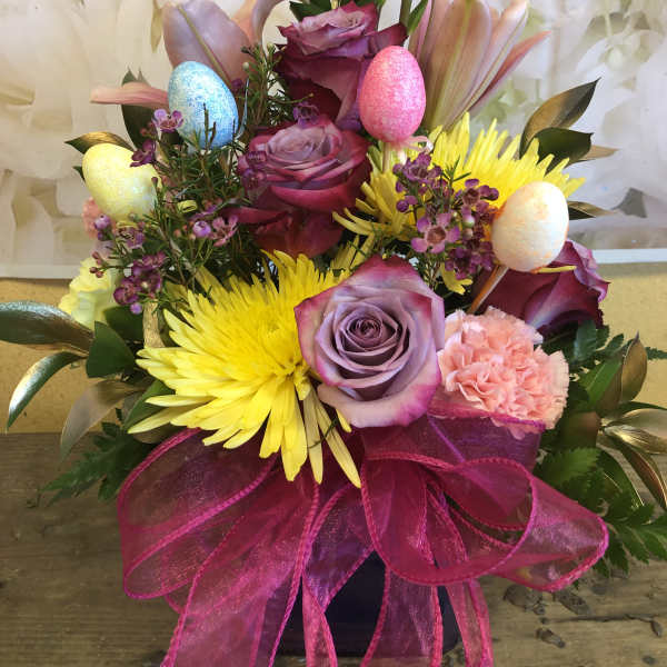 Mixed bouquet with roses, lilies, and bright yellow blooms in a vase
