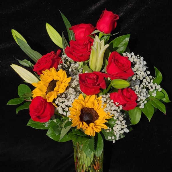 Bouquet of red roses and sunflowers in a clear glass vase