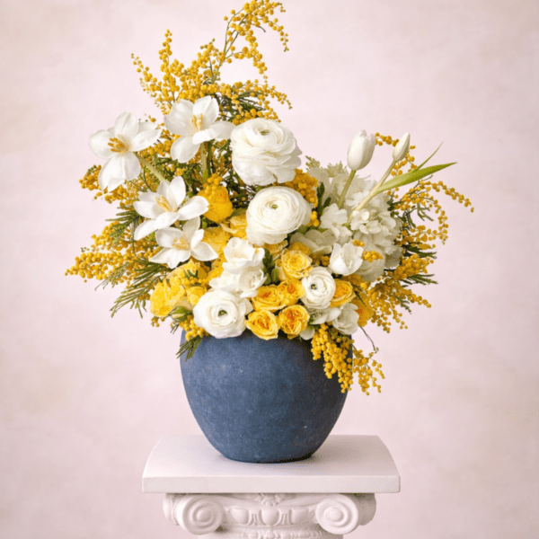 Yellow and white floral arrangement in a blue vase