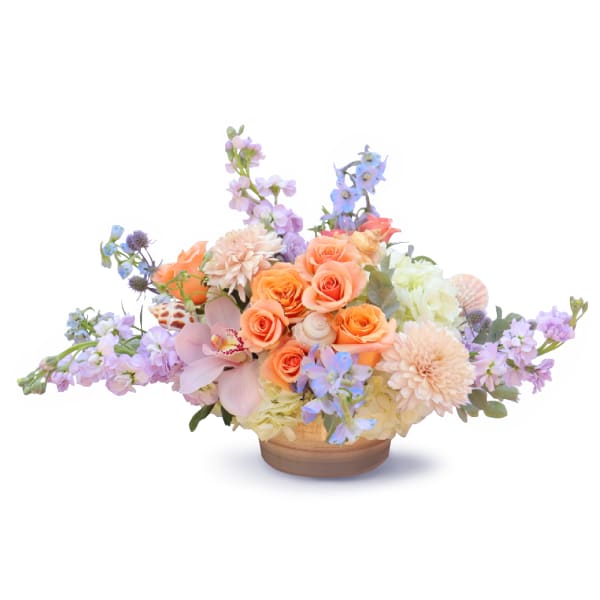 Pastel floral arrangement in a low wooden bowl