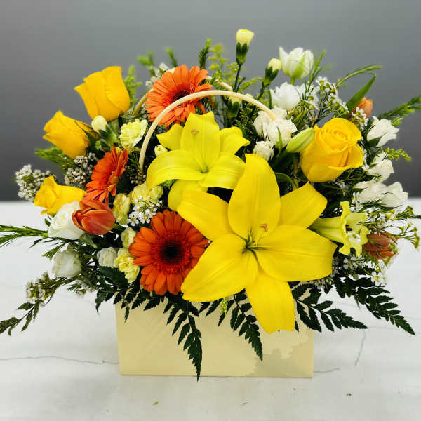 Yellow lilies and roses with orange gerbera daisies in a pale box