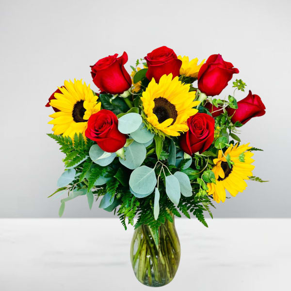 Red roses and yellow sunflowers in a glass vase