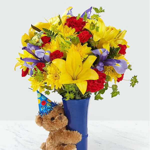 Bouquet of yellow, red, and purple flowers in a blue vase with a teddy bear