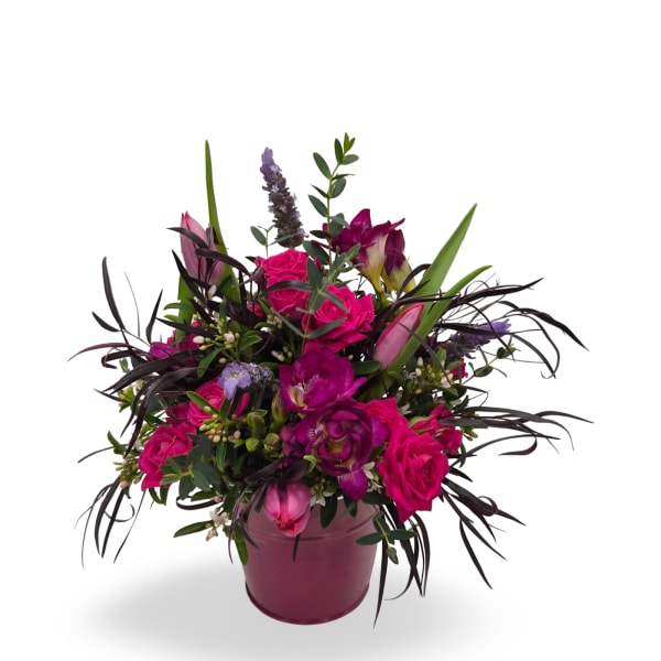 Vibrant arrangement of hot pink roses and purple flowers in a pink ceramic pot