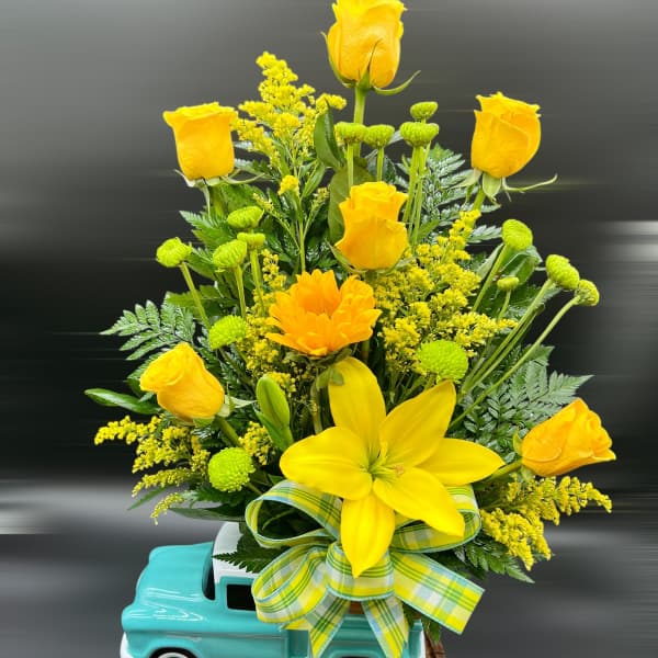 Yellow roses and a lily arranged in a turquoise truck planter