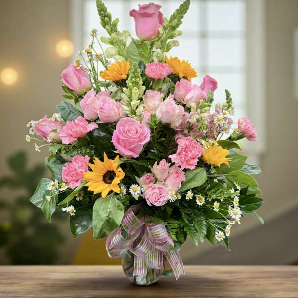 Pink roses and mixed flowers in a glass vase with a ribbon