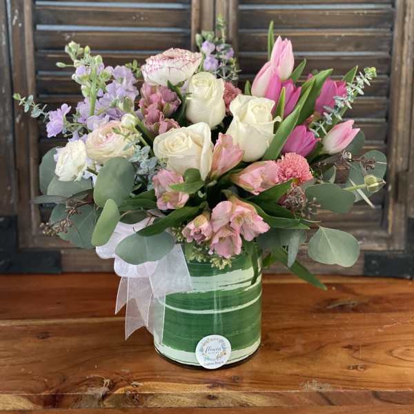 Pink and white mixed flower arrangement in a green striped container