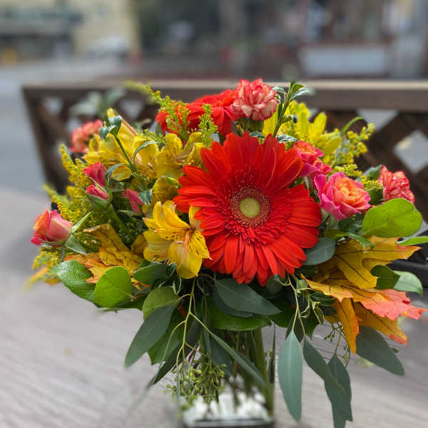 Bouquet of red gerbera daisies and yellow flowers in a glass vase
