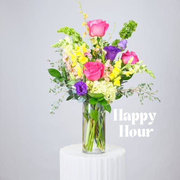 Mixed bouquet of pink, purple, and yellow flowers in a clear glass vase