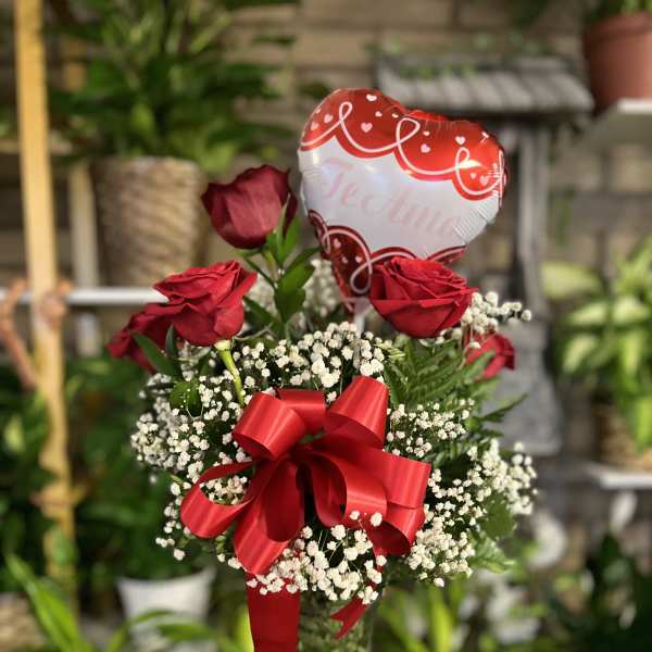 Red roses in a glass vase with a heart balloon and red ribbon