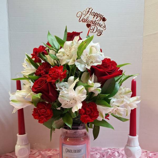 Red and white flower arrangement in a glass jar with a Valentine's Day topper
