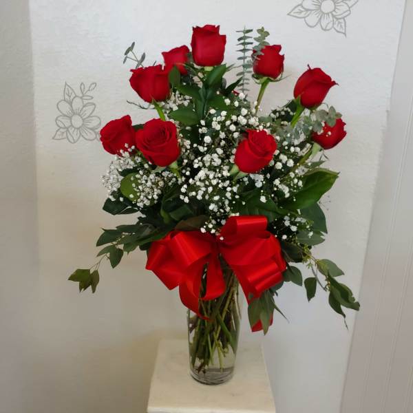 Red roses in a clear glass vase with a red ribbon