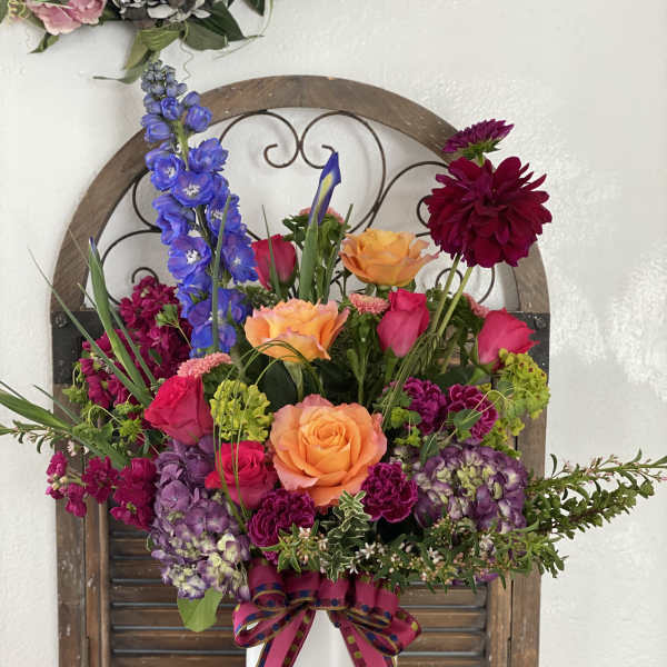 Colorful mixed flower arrangement in a white vase with a ribbon bow