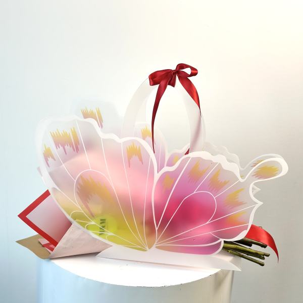 Pink and yellow floral gift bag with a red ribbon bow