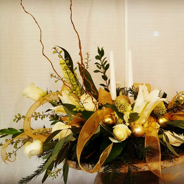 White floral centerpiece with gold ribbon and candles in a low container