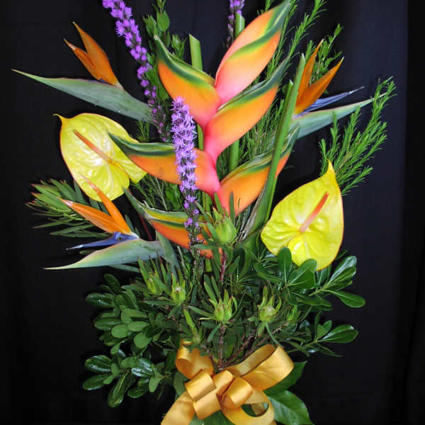 Tropical bouquet with bird of paradise and purple spikes in a glass vase