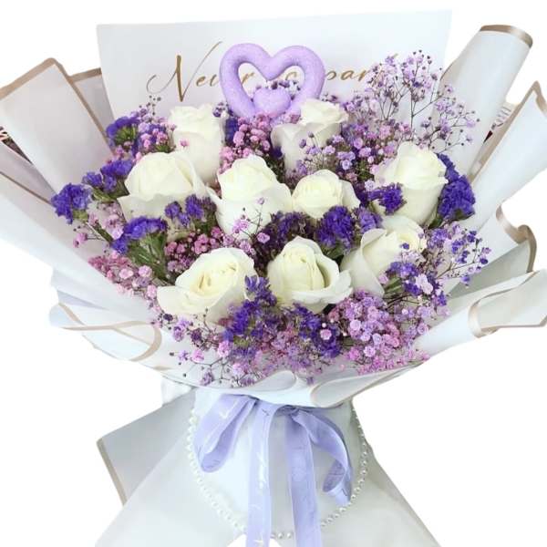 Bouquet of white roses and purple filler flowers wrapped in white paper