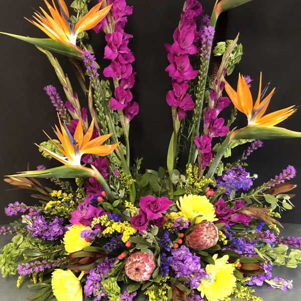 Tropical floral arrangement with orange bird-of-paradise and purple blooms