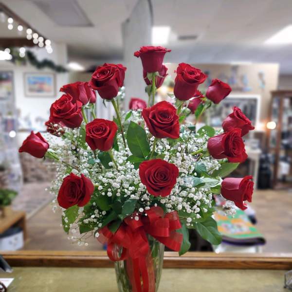 Red roses arranged in a clear glass vase with a red ribbon