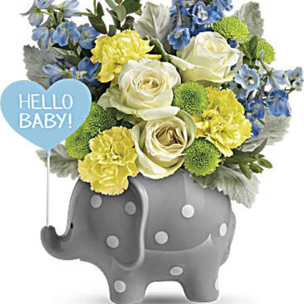 Bouquet of white roses, yellow carnations, and blue flowers in a gray elephant planter with a baby balloon