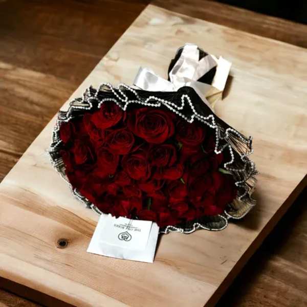 Bouquet of red roses wrapped in black paper with white trim
