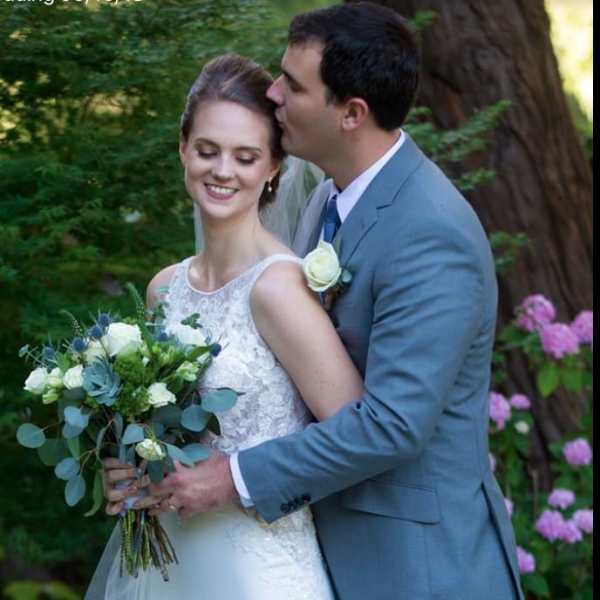 Bride holding a white and blue bouquet beside a groom in a gray suit